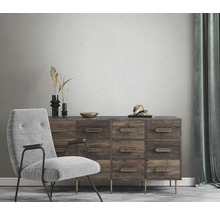 Woonkamer met stoel, ladekast en behang met bloemenmotief