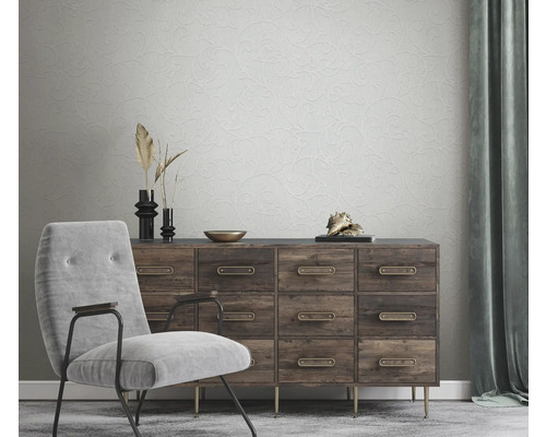 Woonkamer met stoel, ladekast en behang met bloemenmotief