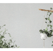 Lichte muur met decoratief behang en hangplant.