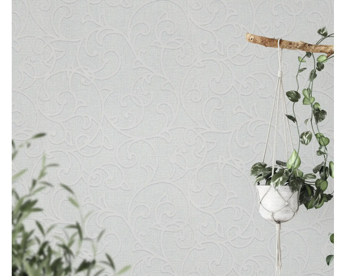 Lichte muur met decoratief behang en hangplant.