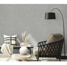 Woonkamer met grijs betonlook behang, fauteuil en vloerlamp