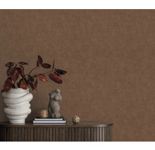 Decoratieve wand met plant in pot, sculptuur en boeken op een donkerhouten kast.