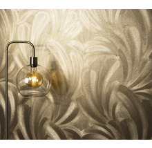 Close-up van een behang met verenmotief naast een vloerlamp met een lamp in een glazen bol