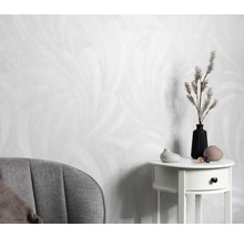 Licht behang met verenontwerp, bijzettafel met vazen en decoratie, fauteuil in de kamer