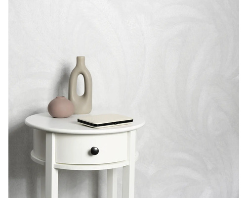 Licht behang met motief achter een wit nachtkastje met decoratie