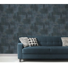 Behang met patroon achter een blauwe bank met kussens