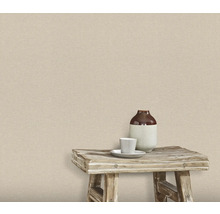 Wand met textielbehang, waarop een kruk met vaas en kopje