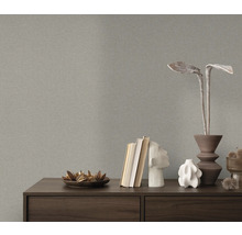 Close-up van een grijs structuurbehang boven een dressoir met decoratieve objecten.