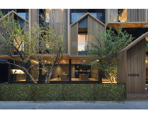 Gevel van een modern gebouw met houten bekleding en begroeiing