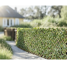 Decoratieve privacyscherm van klimrooster met kunstmatige bladeren in de tuin.