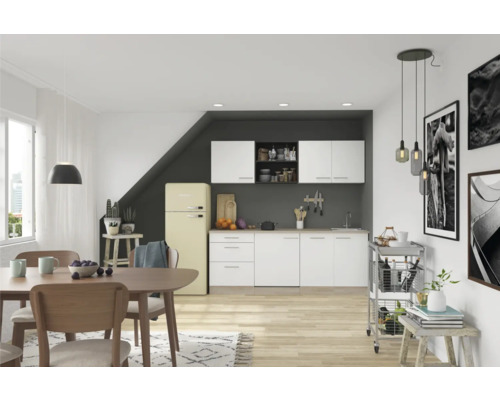 Lichte eethoek met tafel, stoelen, kitchenette en koelkast in een ruim interieur.