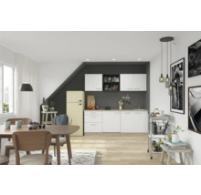 Lichte keuken met eetgedeelte, voorzien van keukenkasten, eettafel, stoelen en een retro koelkast.