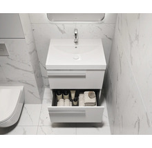 Moderne badkamer met wastafelonderkast en open lade met badkamerbenodigdheden.