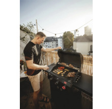 Man grilt groenten en vlees op een gasbarbecue in de buitenlucht