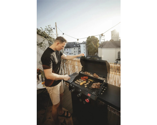 Man grilt groenten en vlees op een gasbarbecue in de buitenlucht