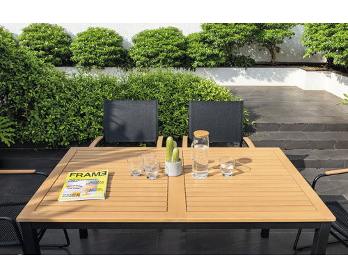 Tuinscene met eettafel, stoelen, glazen, waterkan, tijdschrift en cactus