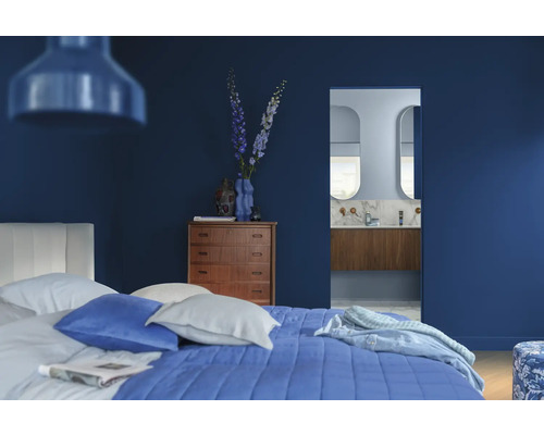 Slaapkamer met bed, commode, decoratie en badkamer op de achtergrond