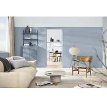 Woonkamer met bank, fauteuil, vloerlamp, planken en kasten in een lichte, georganiseerde ruimte.