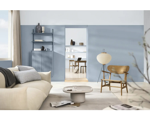 Woonkamer met bank, fauteuil, vloerlamp, planken en kasten in een lichte, georganiseerde ruimte.