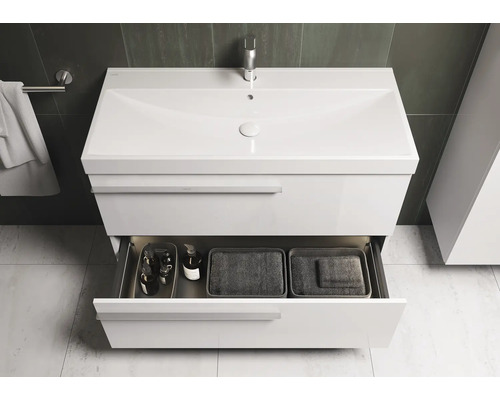 Witte wastafel met open lade met badkamerartikelen en manden