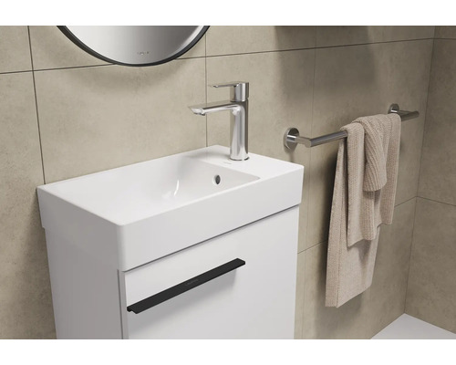 Wastafel met kraan, handdoek en spiegel in de badkamer