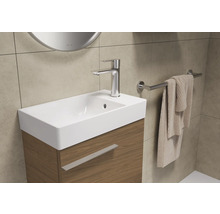 Badkamerwastafel met kraan, handdoek en handdoekhouder.