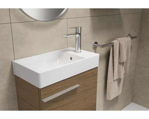 Badkamerwastafel met kraan, handdoek en handdoekhouder.