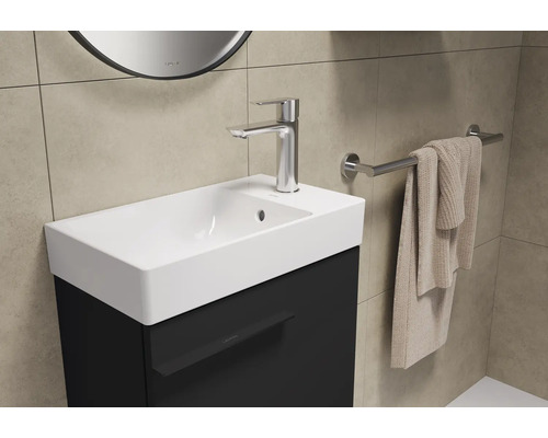 Wastafel met kraan, handdoek en spiegel in de badkamer