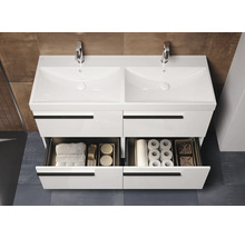 Dubbele wastafelonderkast met twee open laden, armaturen en badkamerbenodigdheden.