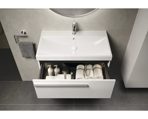 Wastafel met open lade, handdoeken en verzorgingsproducten in moderne badkamer