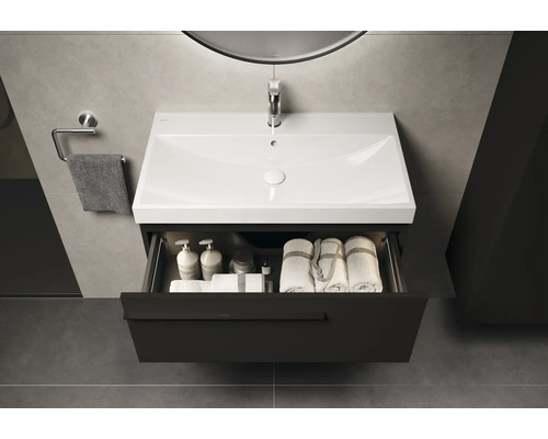 Wastafel met open lade, gevuld met handdoeken en verzorgingsproducten in de badkamer.