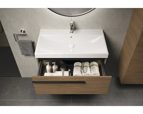 Wastafelonderkast met open lade, wastafel, handdoeken en verzorgingsproducten in een moderne badkamer