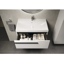 Wastafelmeubel met open lade, handdoeken en toiletartikelen in de badkamer.