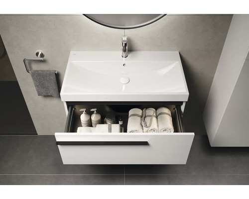 Wastafelmeubel met open lade, handdoeken en toiletartikelen in de badkamer.