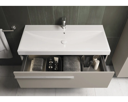 Badkamer met wastafelonderkast, wastafel, kraan en open lade met handdoeken en badkamerbenodigdheden