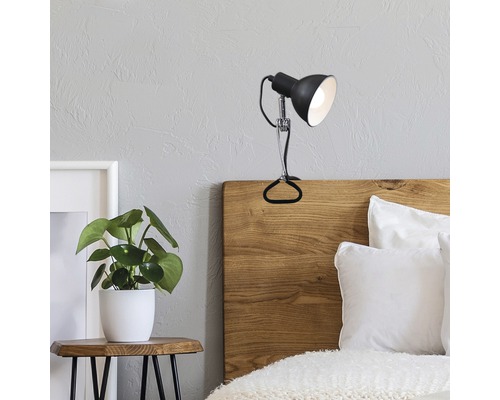 Slaapkamer met bed en een klemspot op een houten hoofdeinde.