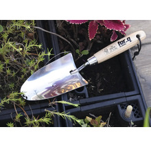 Roestvrijstalen plantgatenschep met houten handvat in een tuinperk