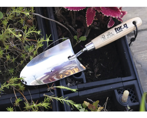 Roestvrijstalen plantgatenschep met houten handvat in een tuinperk