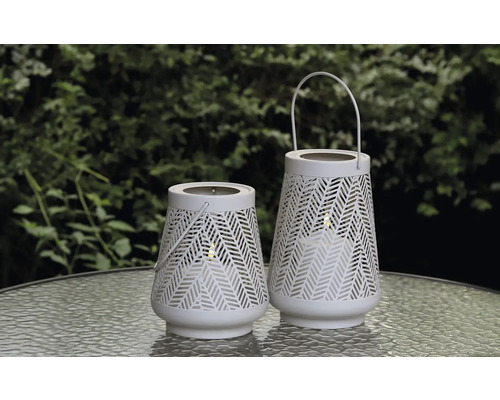 Twee witte tuinlantaarns met patroon op een tafel