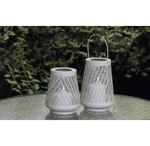 Twee witte windlichten met patroon op een tafel