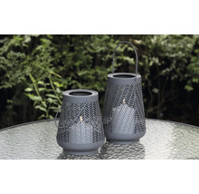 Twee decoratieve windlichten met kaarsen op een tafel buiten.