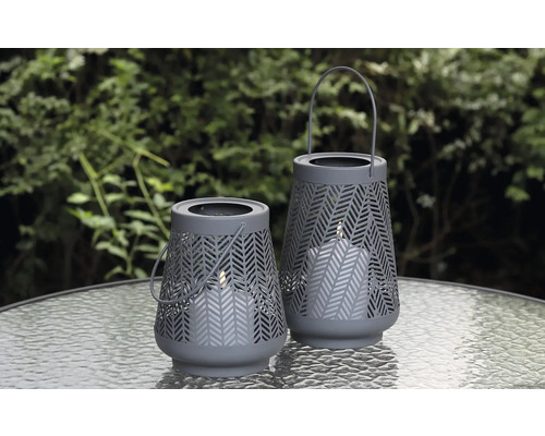 Twee decoratieve windlichten met kaarsen op een tafel buiten.