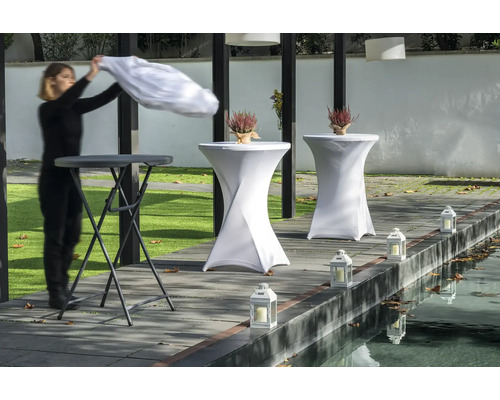 Scene met statafels, tafelhoezen, lantaarns en een persoon die een doek oplegt.