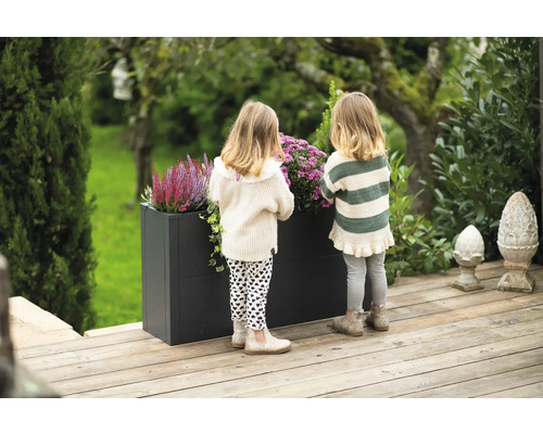 Scène met twee kinderen bij een plantenbak in de tuin