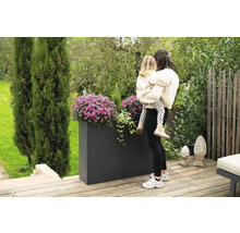 Rechthoekige metalen plantenbak met bloemen en moeder met kind in de tuin