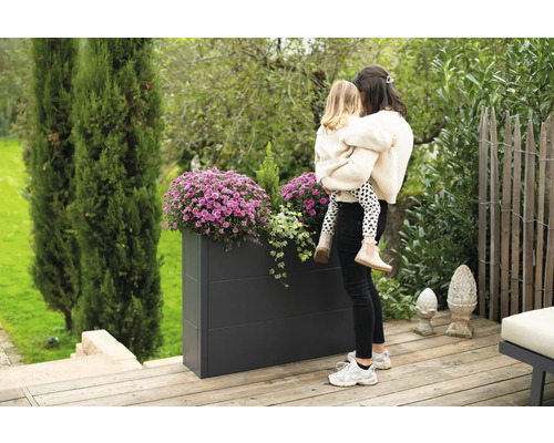 Rechthoekige metalen plantenbak met bloemen en moeder met kind in de tuin