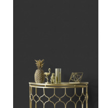 Decoratieve gouden ananas, flamingo, aap, vaas en geometrische figuur op een gouden bijzettafel tegen een donkere wand.