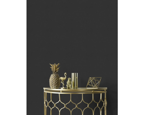 Decoratieve gouden ananas, flamingo, aap, vaas en geometrische figuur op een gouden bijzettafel tegen een donkere wand.