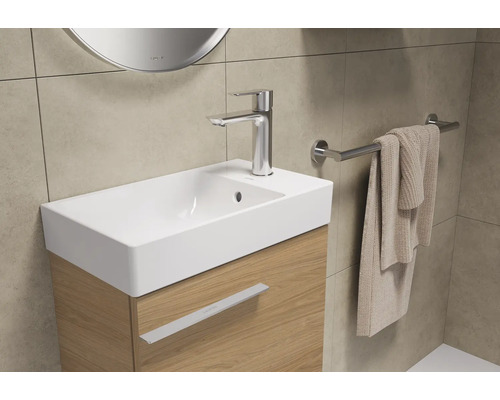 Wastafel met kraan, handdoekhouder en handdoek in een badkamer