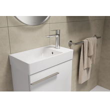 Wastafelmeubel met kraan, handdoek en spiegel in een badkamer.